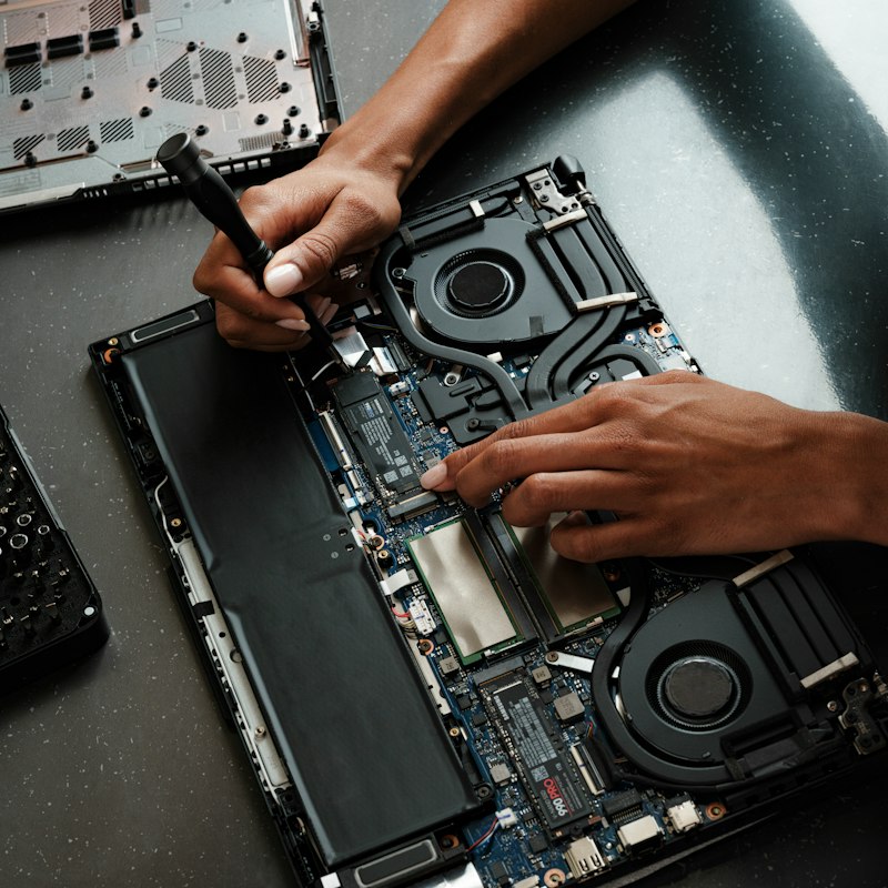 Technician repairing the internals of a laptop on a workbench